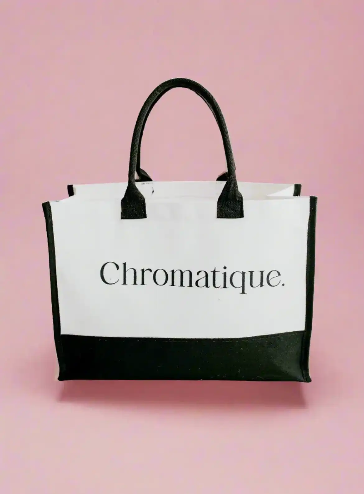 Black and white "Chromatique" tote bag against a pink background.